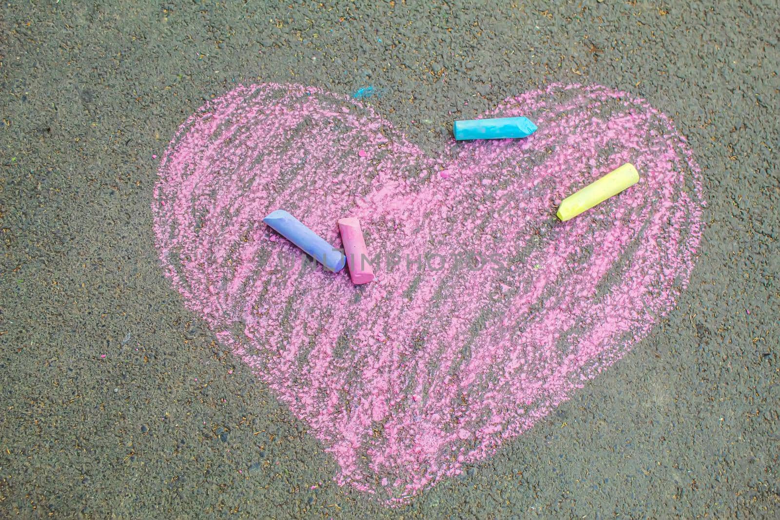 child painted a heart on the asphalt with chalk. selective focus by mila1784
