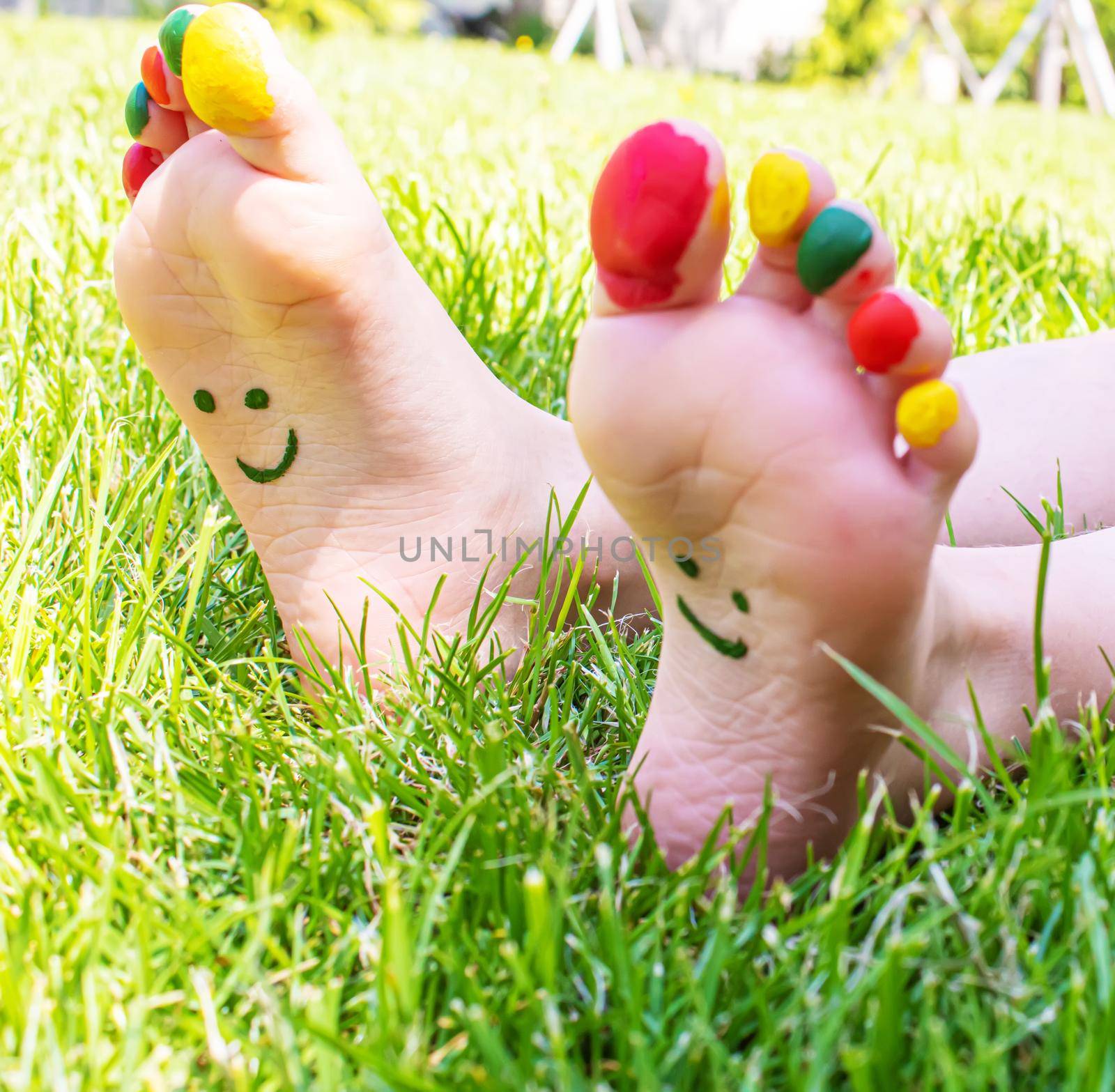 Children's feet with a pattern of paints smile on the green grass. Selective focus. nature.