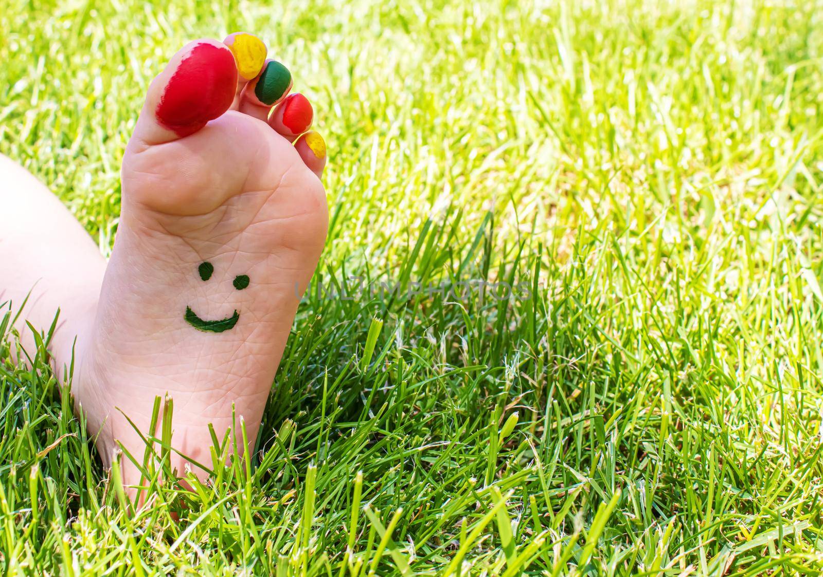 Children's feet with a pattern of paints smile on the green grass. Selective focus. nature.