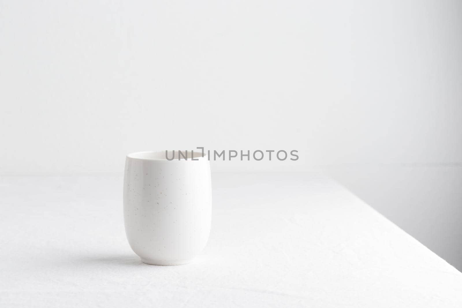 White teacup on a table on a white background