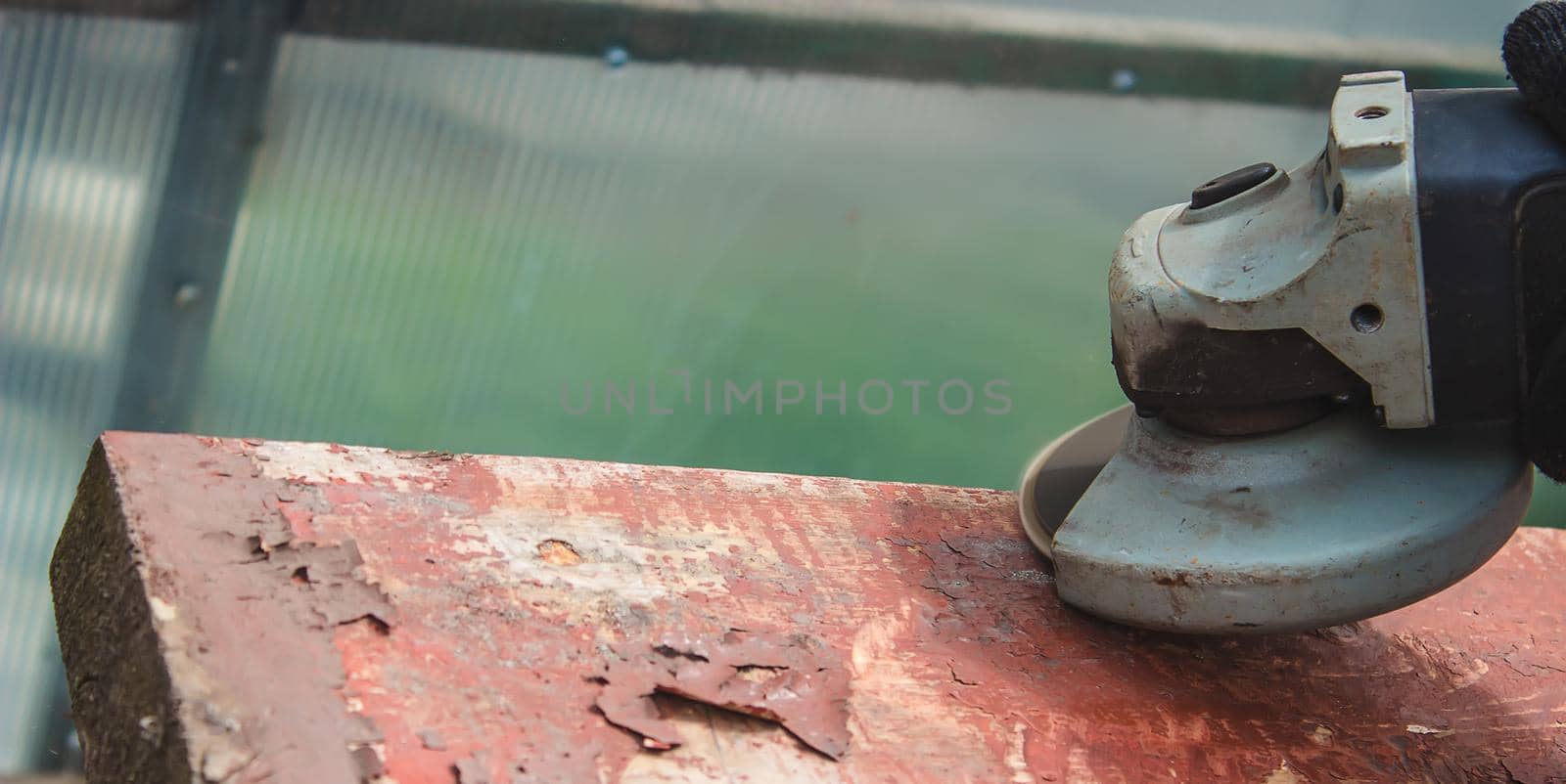 a man is grinding a board. Removing old paint from boards. Carpentry work. selective focus