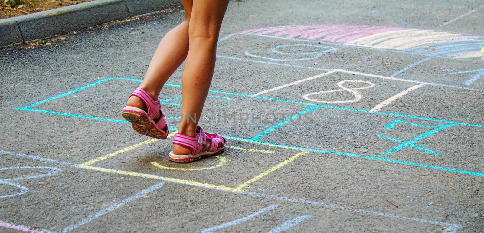 Child jumping classics on the pavement. Selective focus. by mila1784