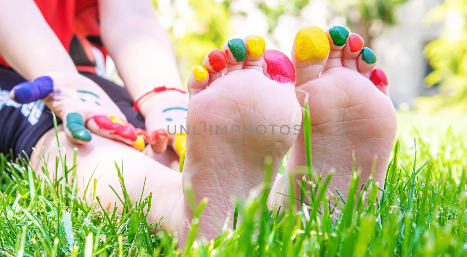 Children's feet with a pattern of paints smile on the green grass. Selective focus. nature.