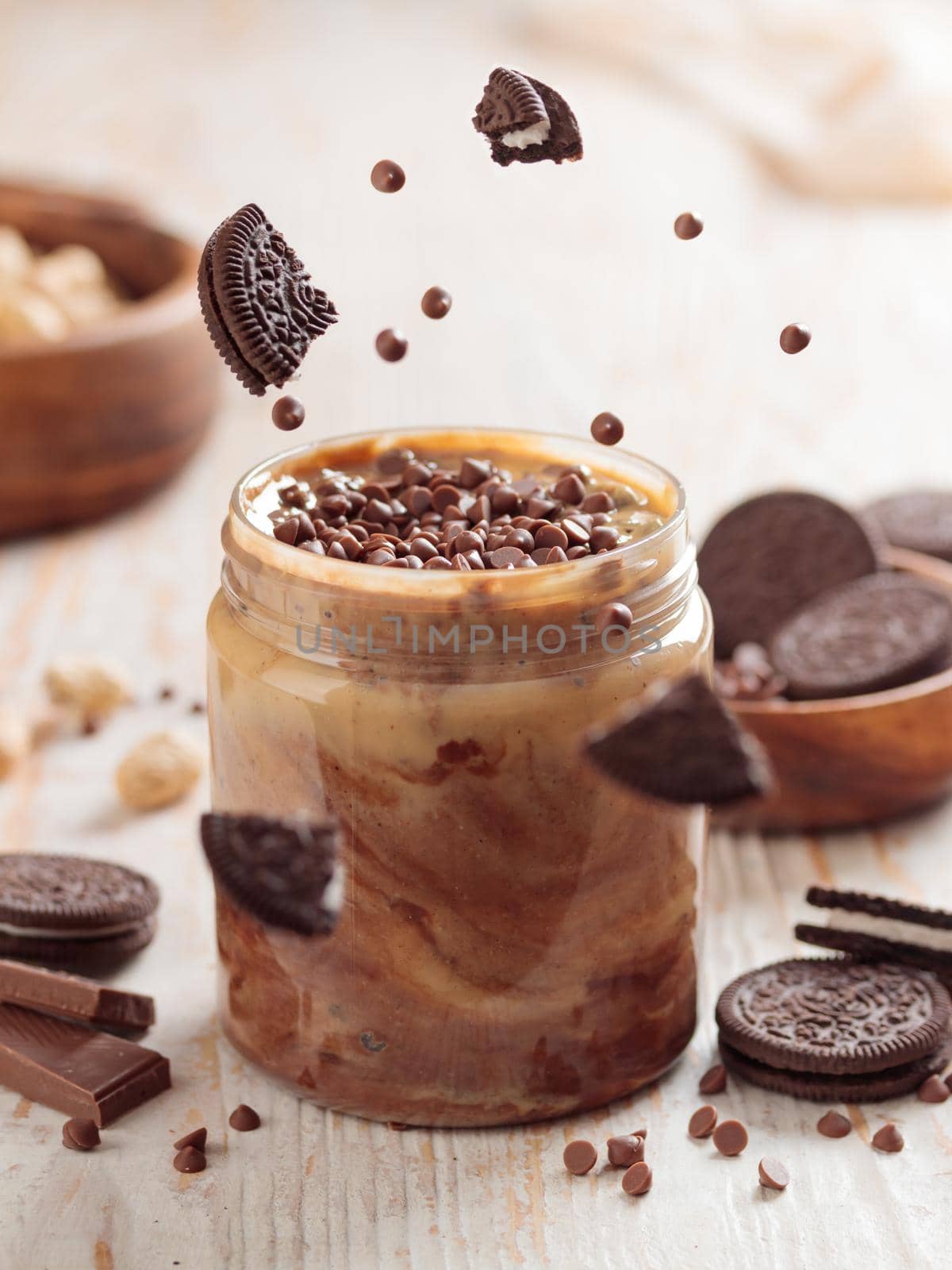 Jar with peanut butter and sweet ingredients on white wooden background closeup