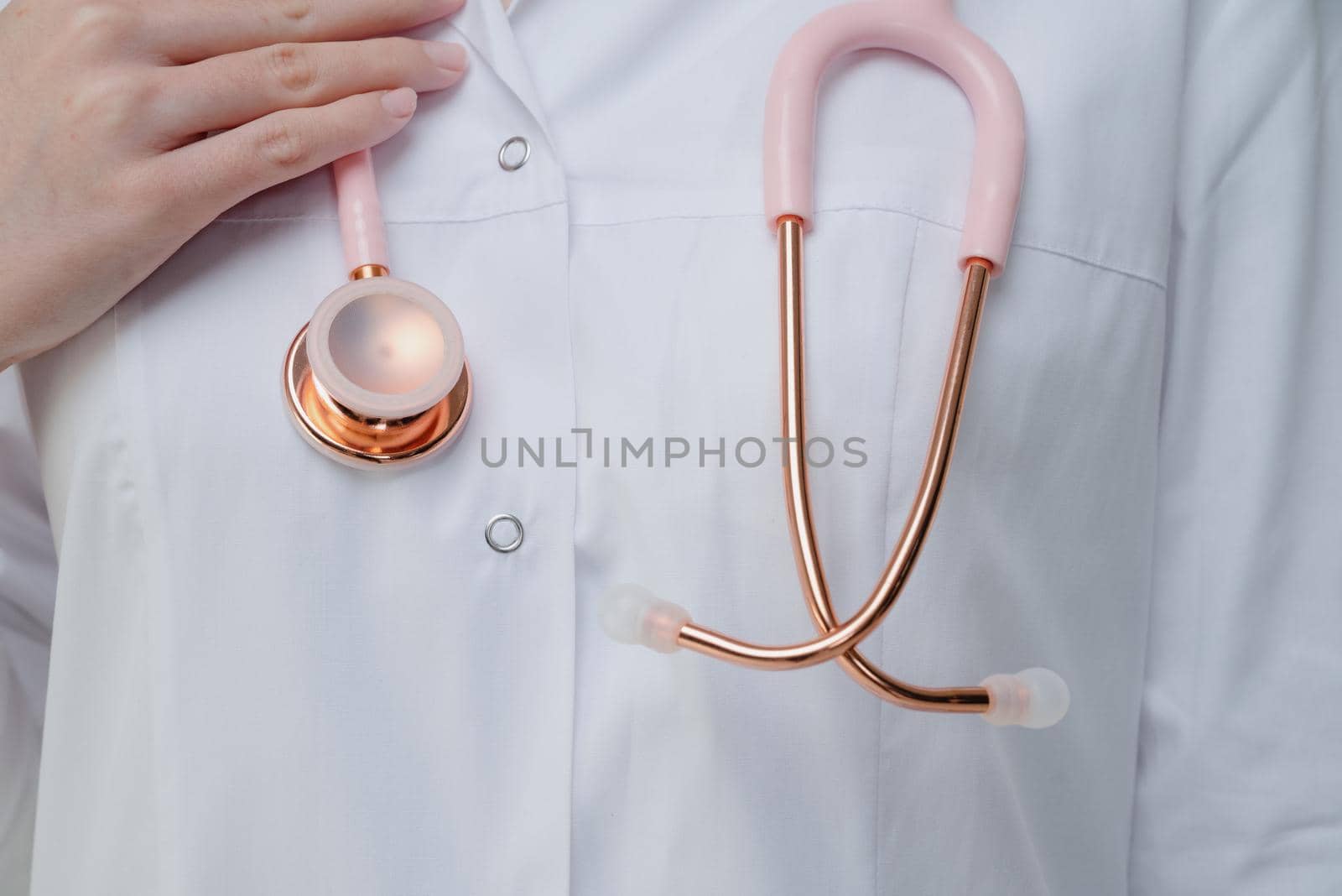 Pink medical stethoscope.A doctor with a stethoscope.A doctor holding a stethoscope.The concept of healthcare.