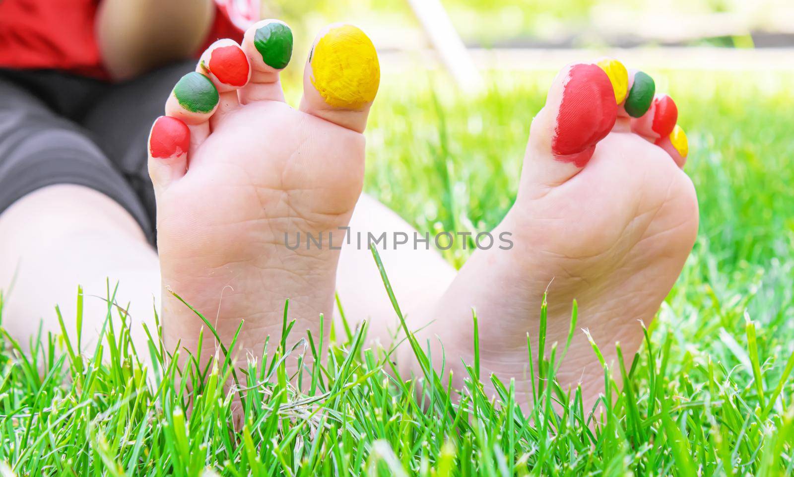 Children's feet with a pattern of paints smile on the green grass. Selective focus. nature.