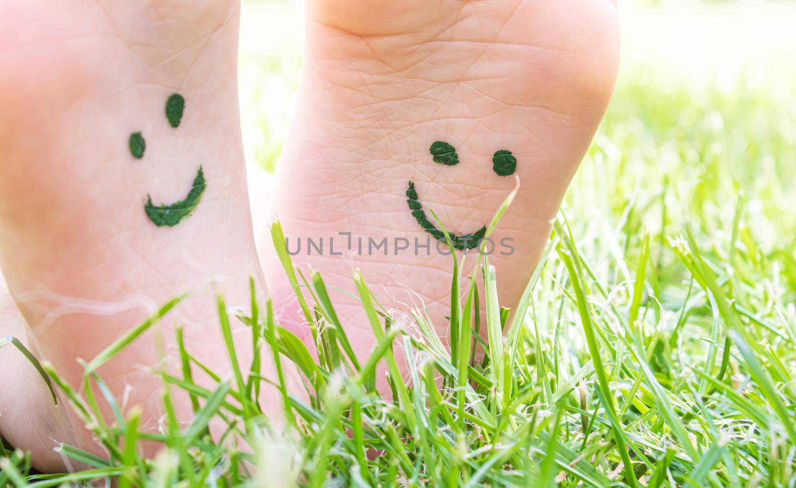 Children's feet with a pattern of paints smile on the green grass. Selective focus. nature.