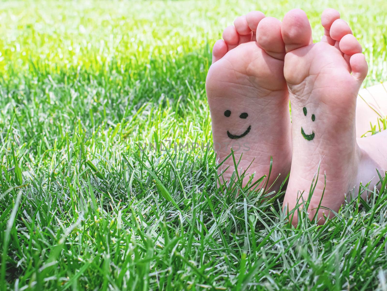 Children's feet with a pattern of paints smile on the green grass. Selective focus. nature.