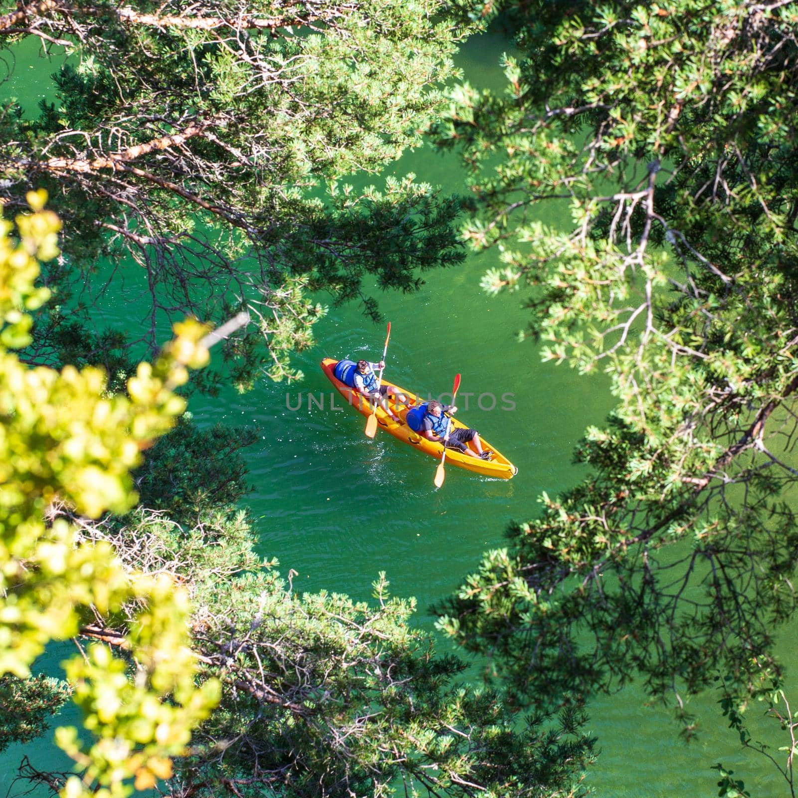 Orange canoe-kayak seen through the trees by Tilo