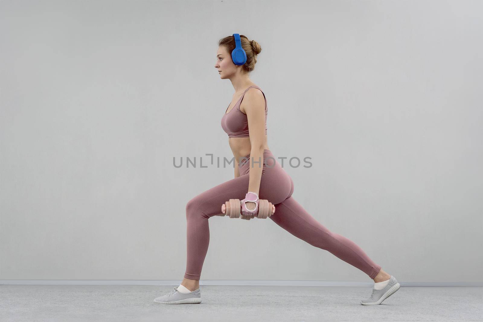 Doing step split stretch athletic young woman use heavy lifting using dumbbell at the gym. Young woman exercise using dumbbell to lose weight or burn calories. Sport concept.