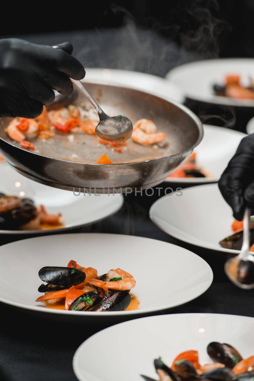 the chef prepares a seafood dish. frying pan with seafood and lemon and basil. shrimp squid and mussels fried in white. by Ashtray25