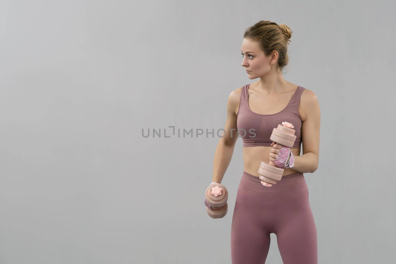 Young woman exercise using dumbbell to lose weight or burn calories. Athletic young woman doing heavy lifting using dumbbell at the gym. Healthy life concept.