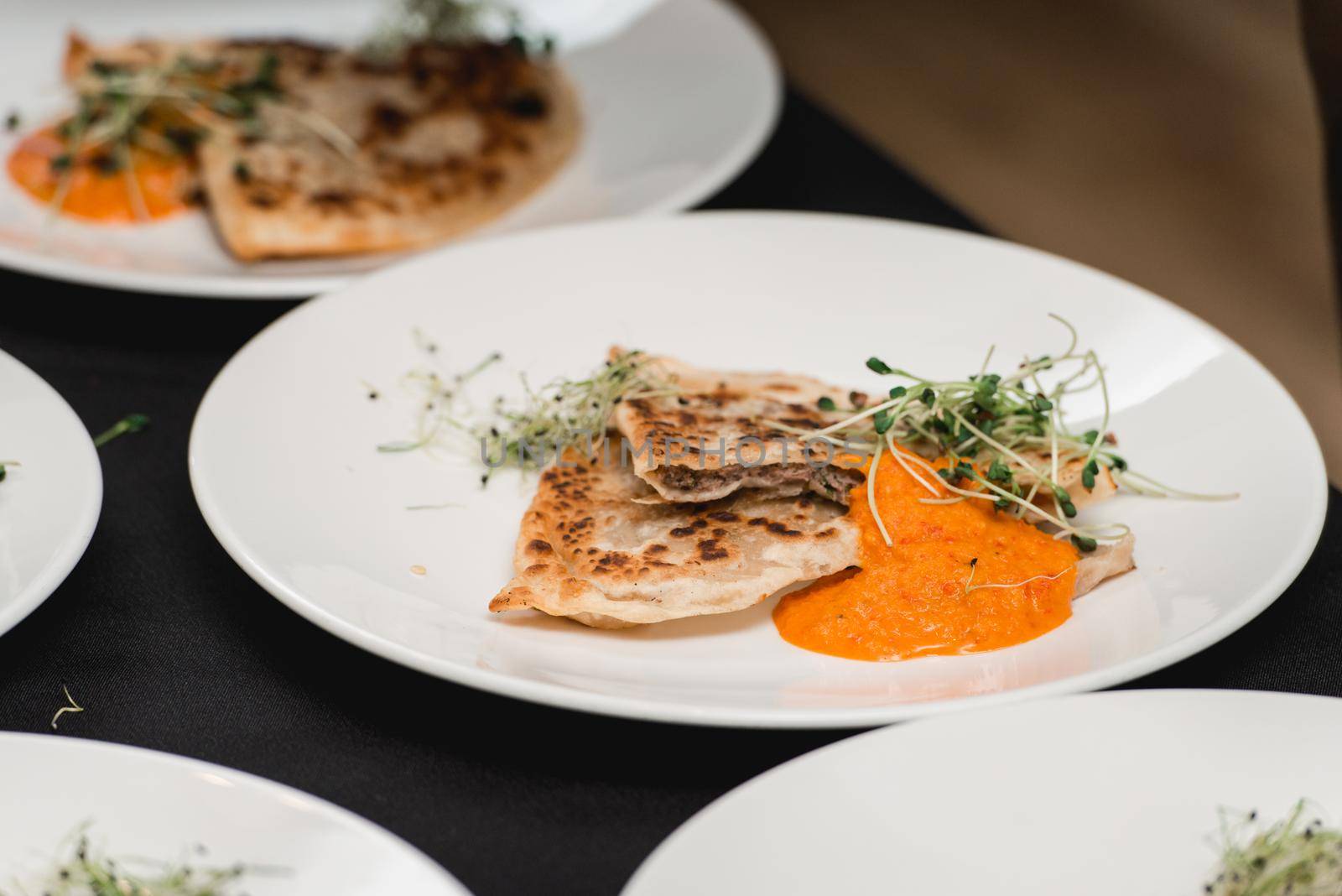 Cheburek traditional balkan meat pastry pie with herbs on a white plate. Served with sauce and micro green by Ashtray25