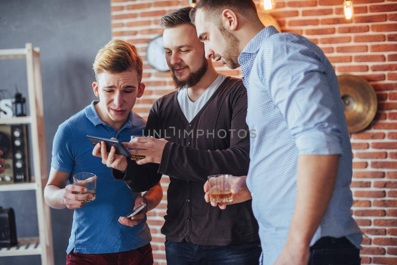 Cheerful old friends communicate with each other and phone watch, with glasses of whiskey in pub. Concept of entertainment and lifestyle. Wifi connected people in bar table meeting.