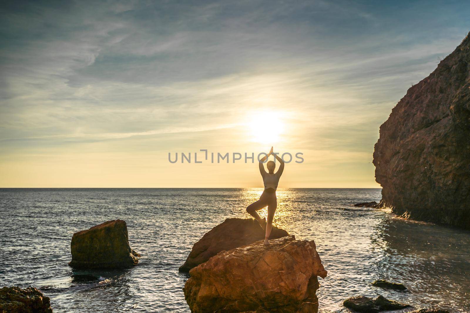 Girl gymnast is training on the beach by the sea sunset. Does twine. Photo series. by Matiunina