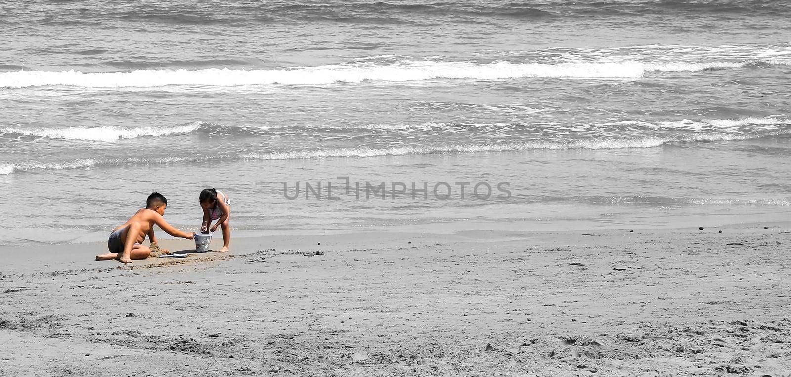 Arenales del Sol, Alicante, Spain- May 8, 2022: Children playing with the sand by the shore on the beach on a Sunny day of Spring in Alicante