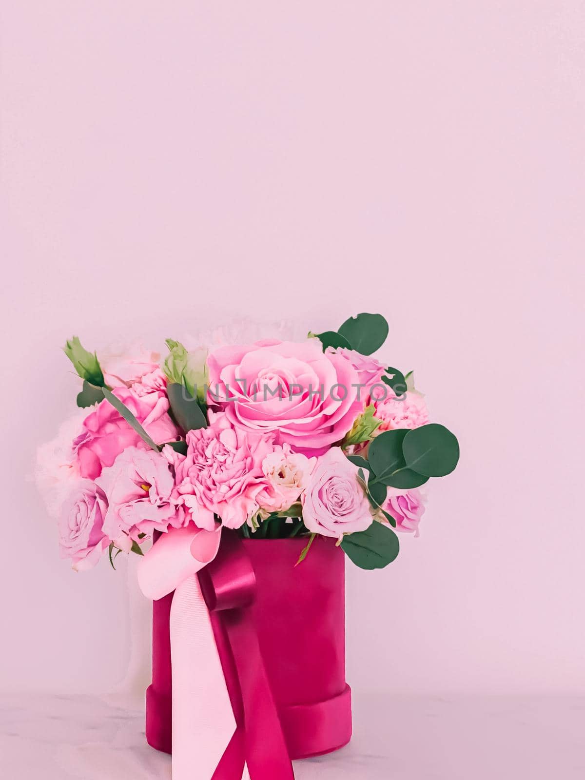 Beautiful bouquet of blooming flowers in flower box on pink background, holiday gift, luxury floral design concept