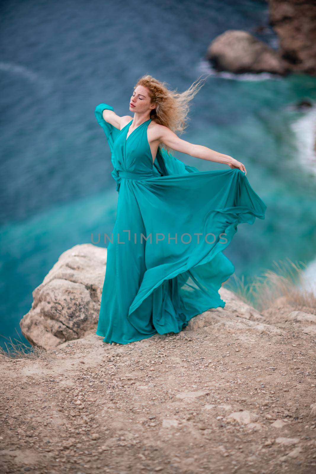 A woman in an emerald dress, a fashion model with long silk wings in a flowing dress, flying fabric on the embankment. by Matiunina