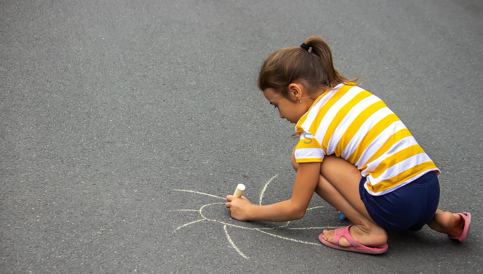 the child draws with chalk on the pavement, the heart is the sun. Nature. selective focus