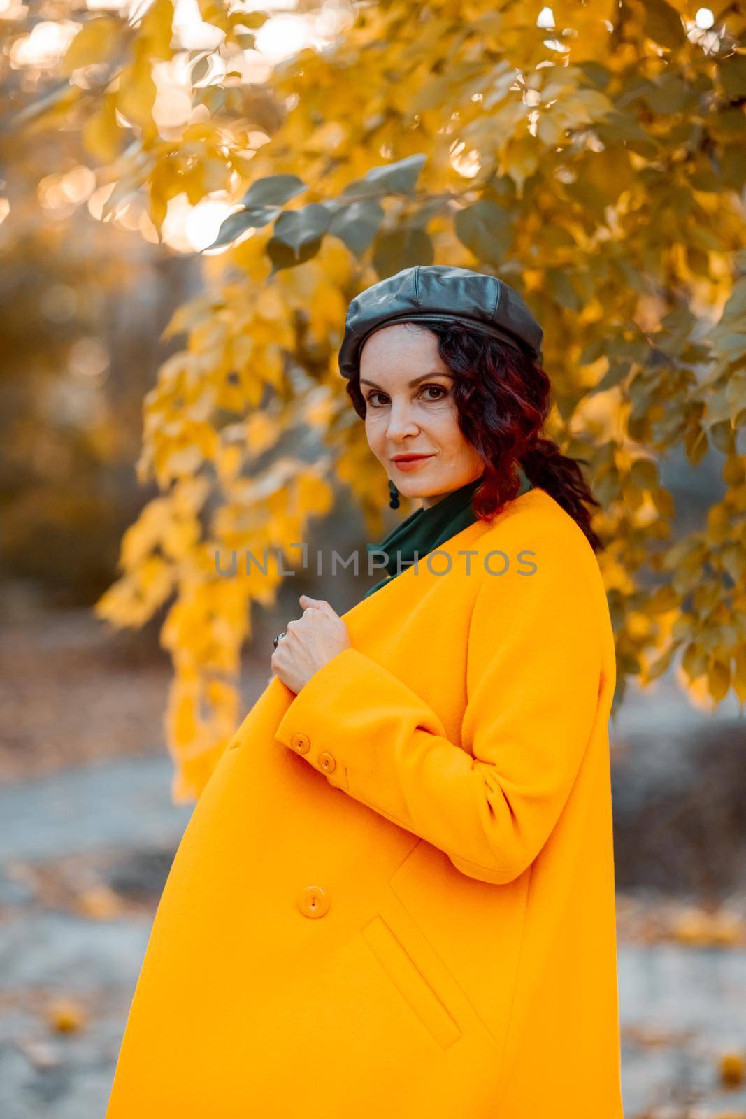 Beautiful woman walks outdoors in autumn. She is wearing a yellow coat and a green dress. Young woman enjoying the autumn weather. Autumn content