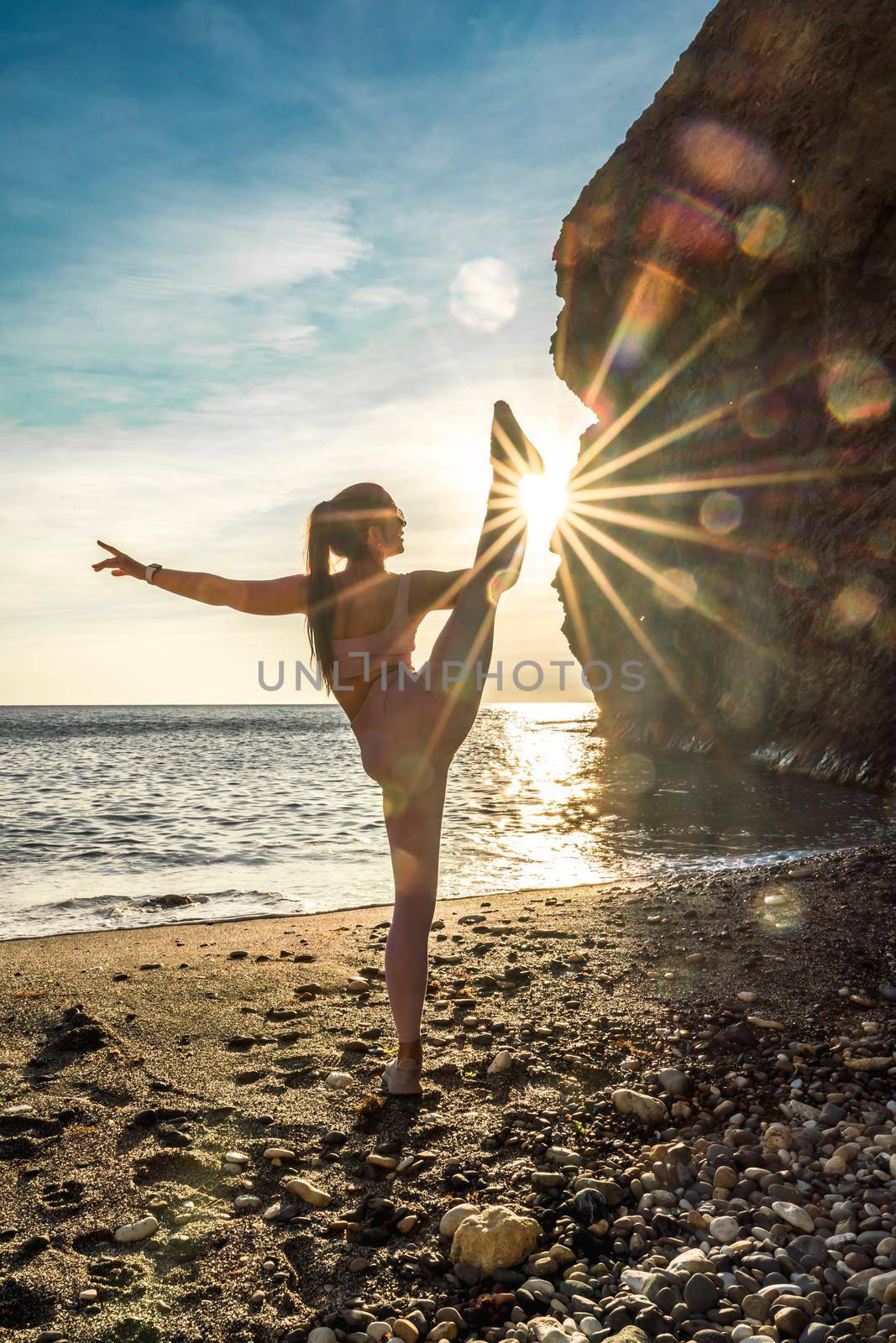 Girl gymnast is training on the beach by the sea sunset. Does twine. Photo series