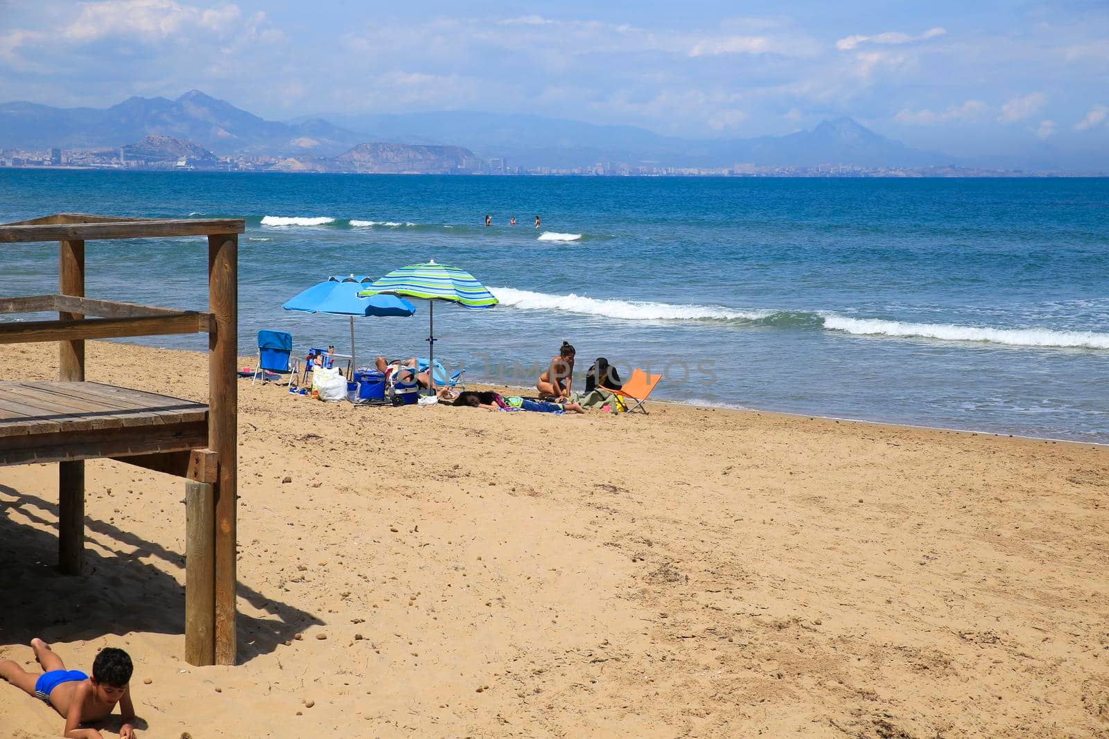 Arenales del Sol, Alicante, Spain- May 8, 2022: People sunbathing by the shore on the beach on a Sunny day of Spring