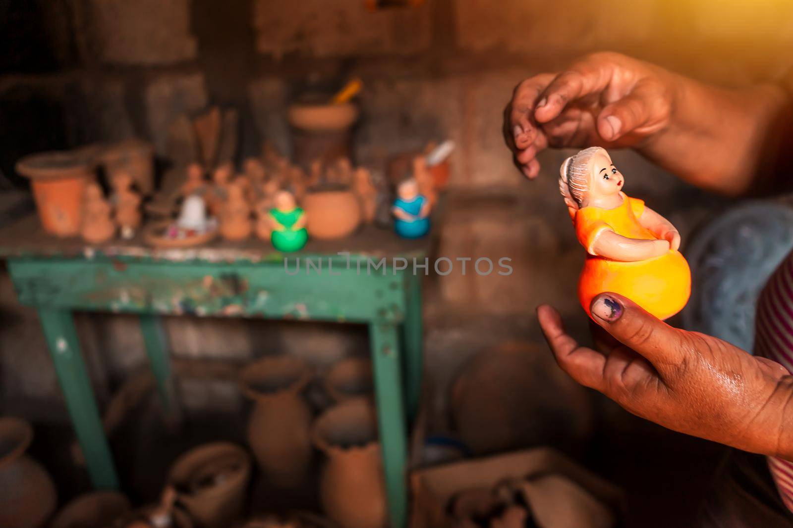 Closeup to the hands of a master craftswoman holding a clay doll made in her workshop in La Paz Centro Nicaragua. Concept of business and crafts in Latin America.