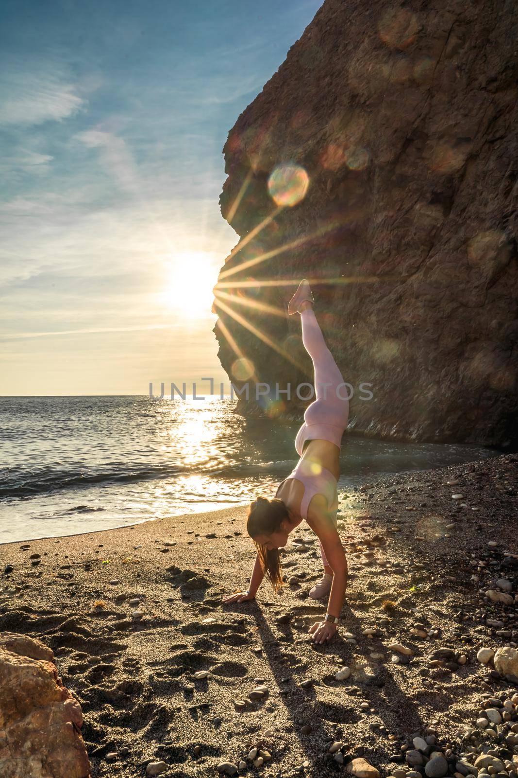 Girl gymnast is training on the beach by the sea sunset. Does twine. Photo series