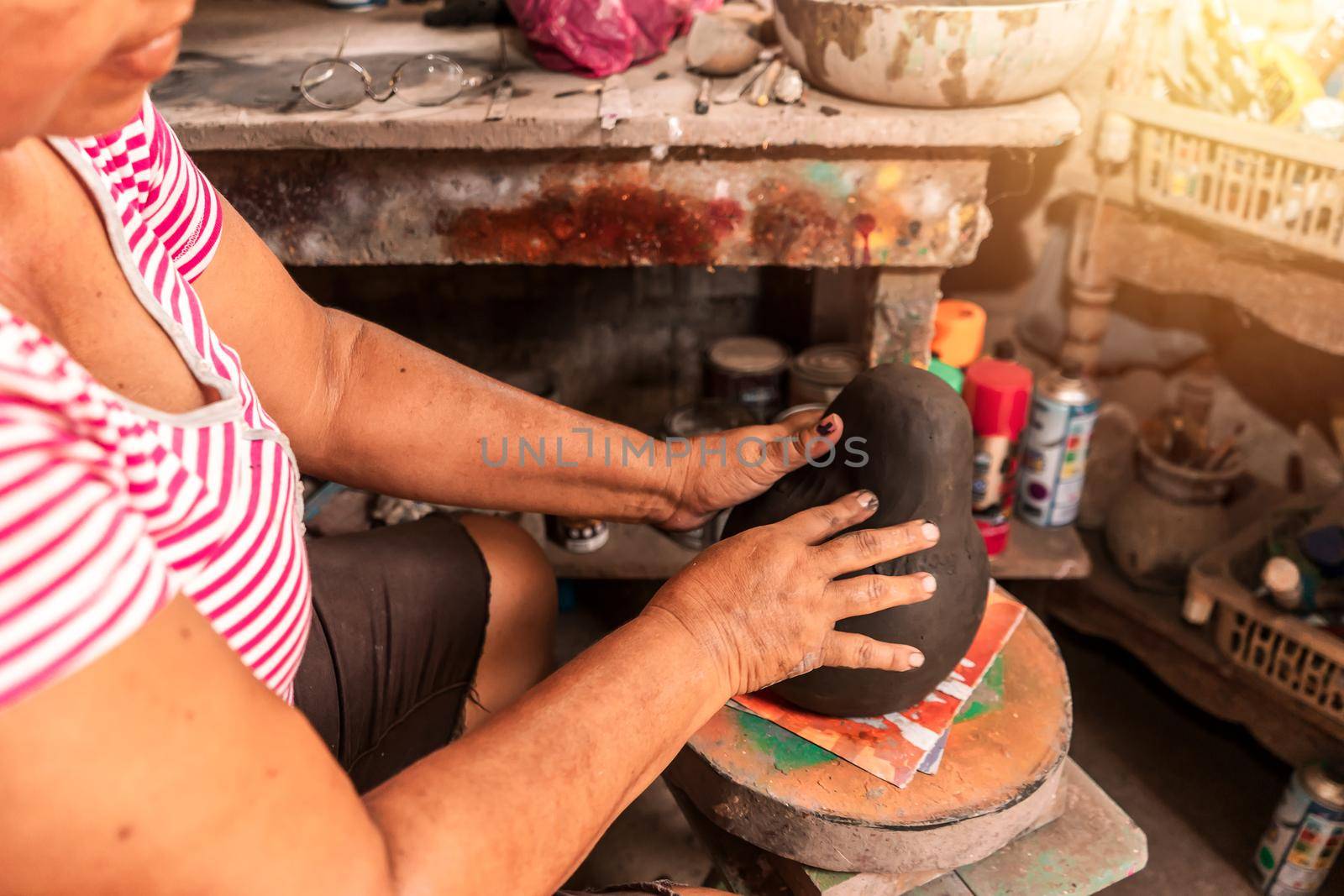 Closeup on the hands of a sculpture artisan from La Paz Centro in Leon Nicaragua putting together a clay doll to sell in her small local business.
