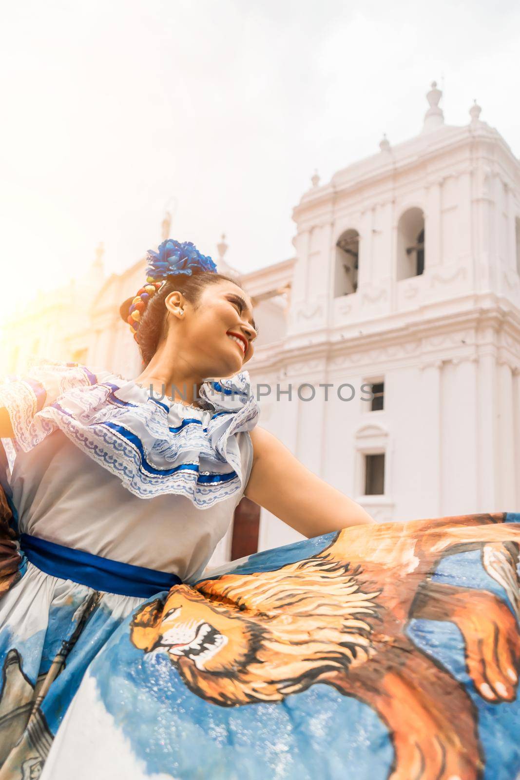 Vertical photo of a Latin woman in a traditional dress from Nicaragua dancing in front of a colonial church. Concept of culture and traditions