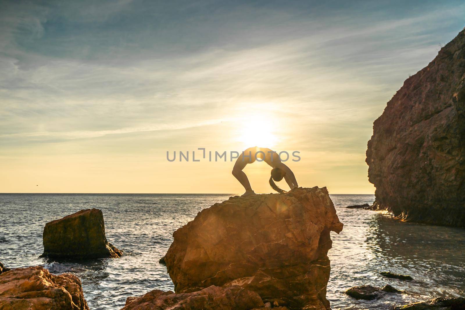 Girl gymnast is training on the beach by the sea sunset. Does twine. Photo series