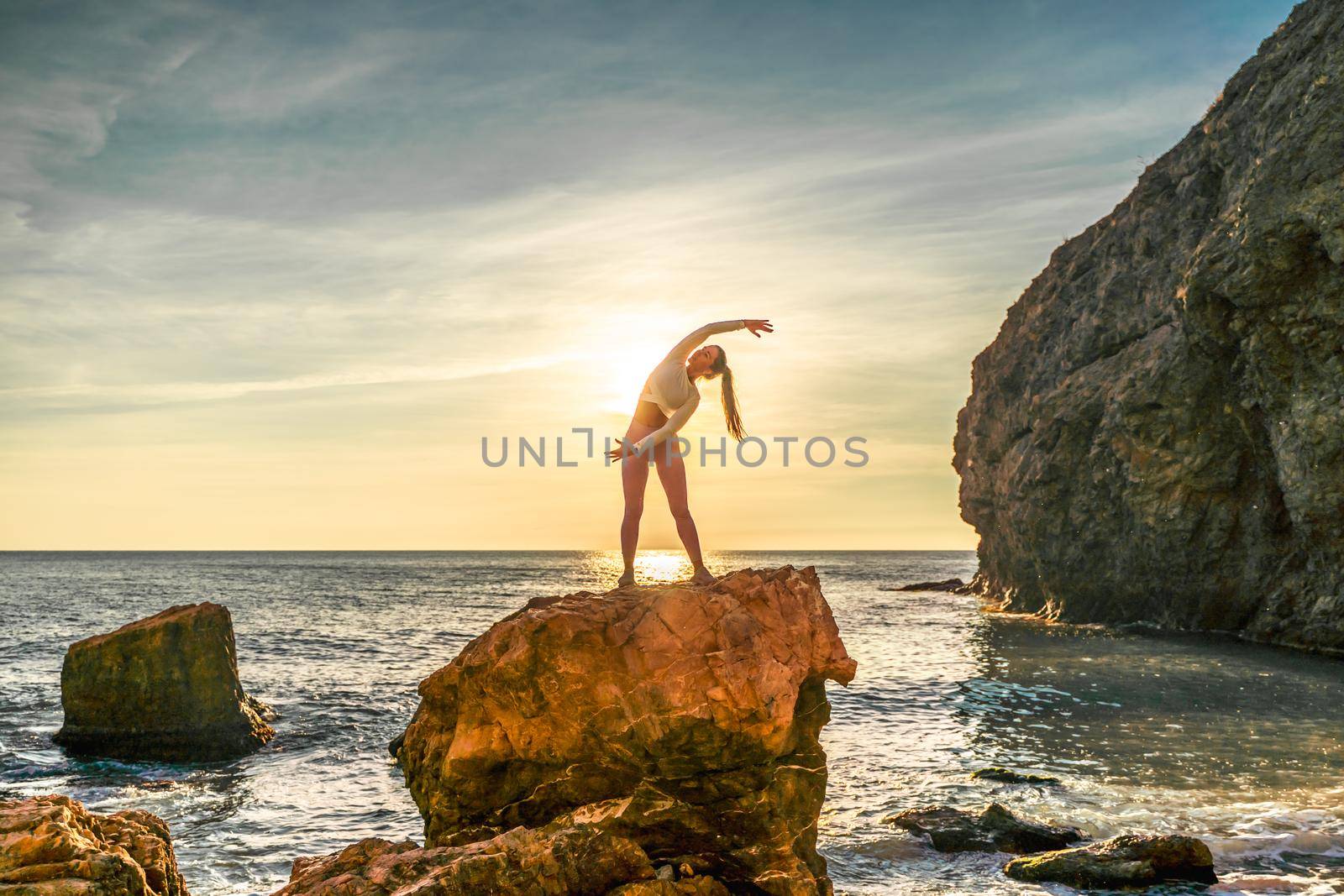 Girl gymnast is training on the beach by the sea sunset. Does twine. Photo series