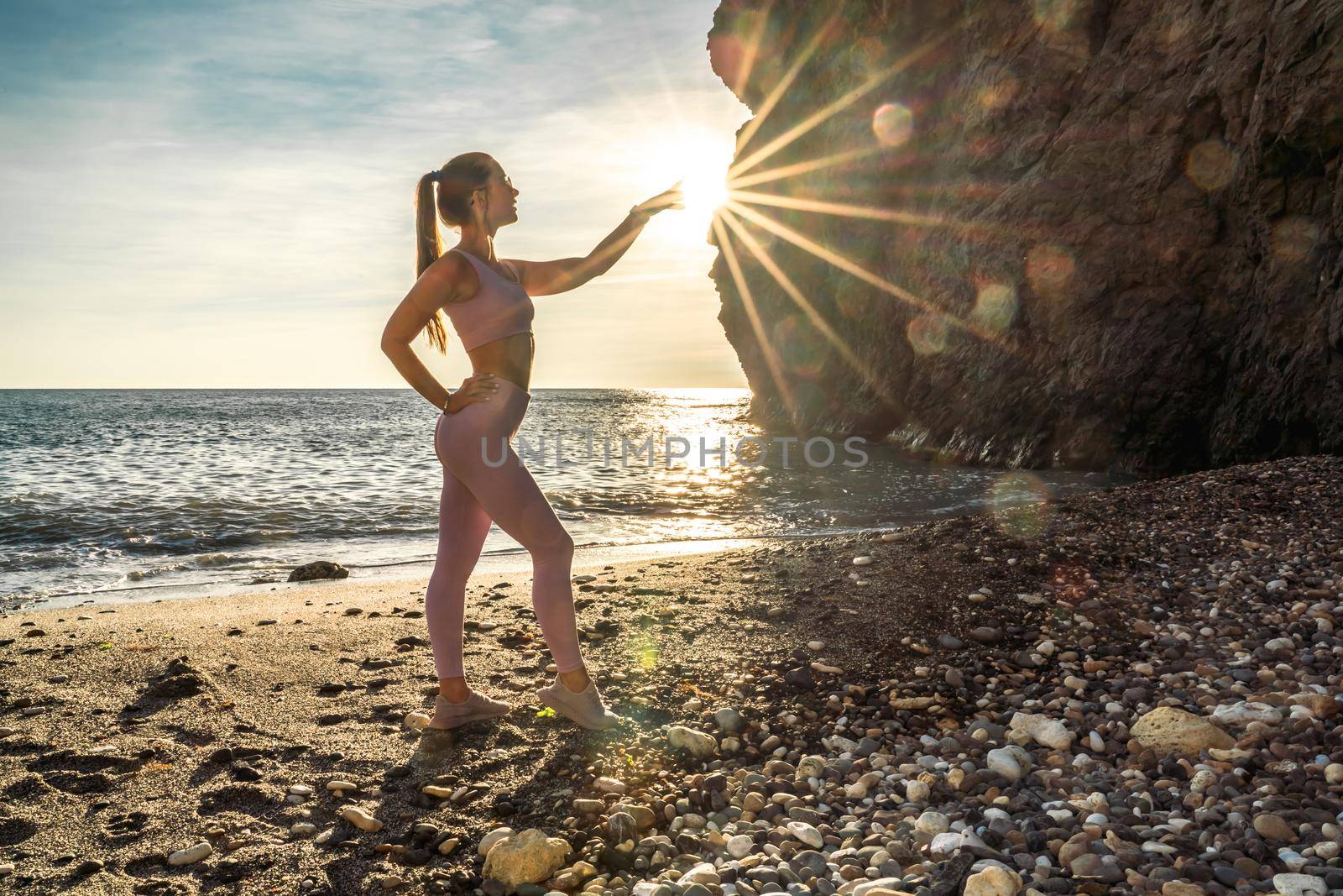 Girl gymnast is training on the beach by the sea sunset. Does twine. Photo series. by Matiunina