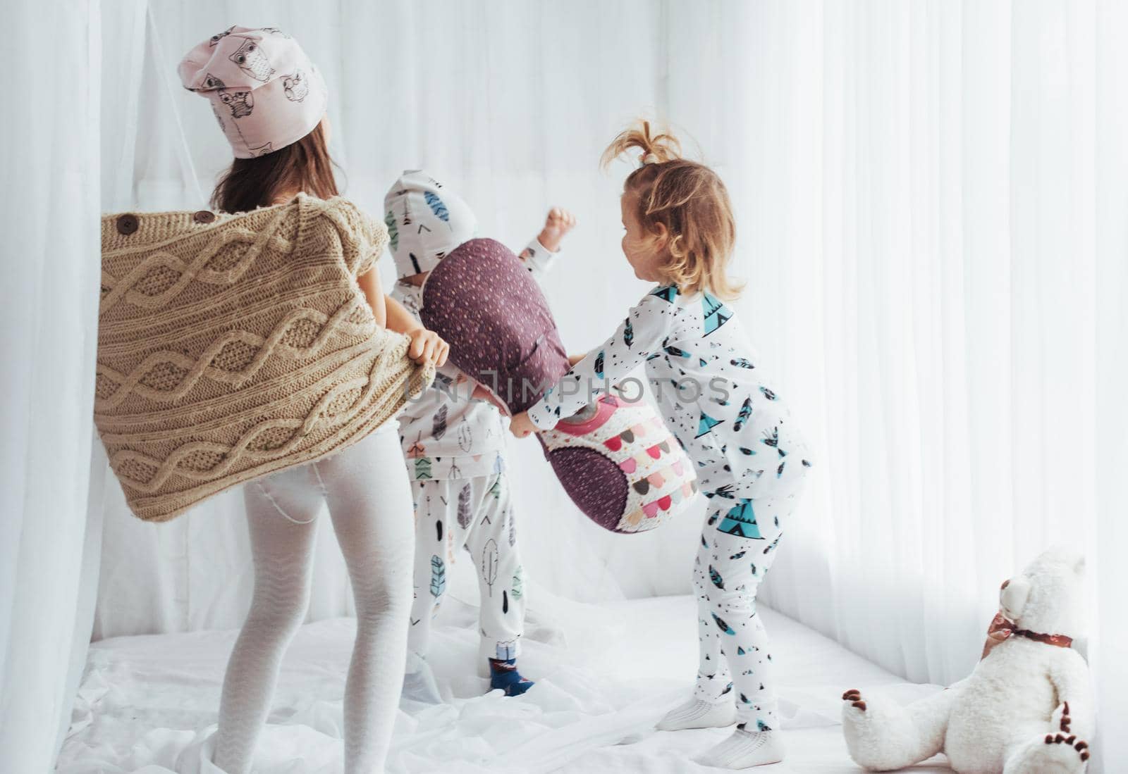 Children in soft warm pajamas playing in bed