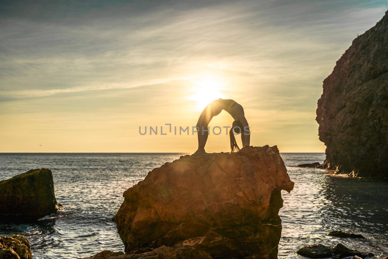 Girl gymnast is training on the beach by the sea sunset. Does twine. Photo series. by Matiunina