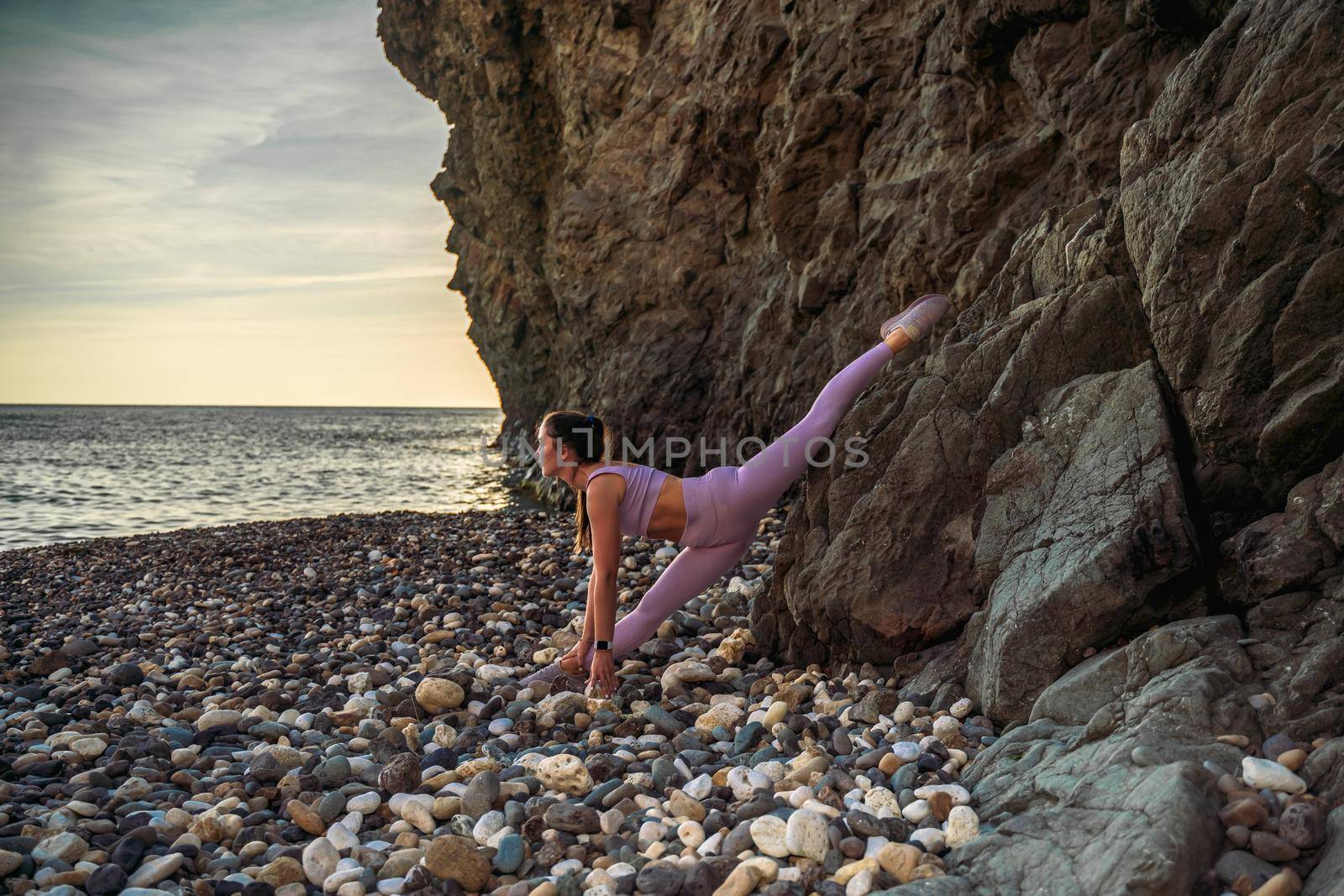 Girl gymnast is training on the beach by the sea. Does twine. Photo series by Matiunina