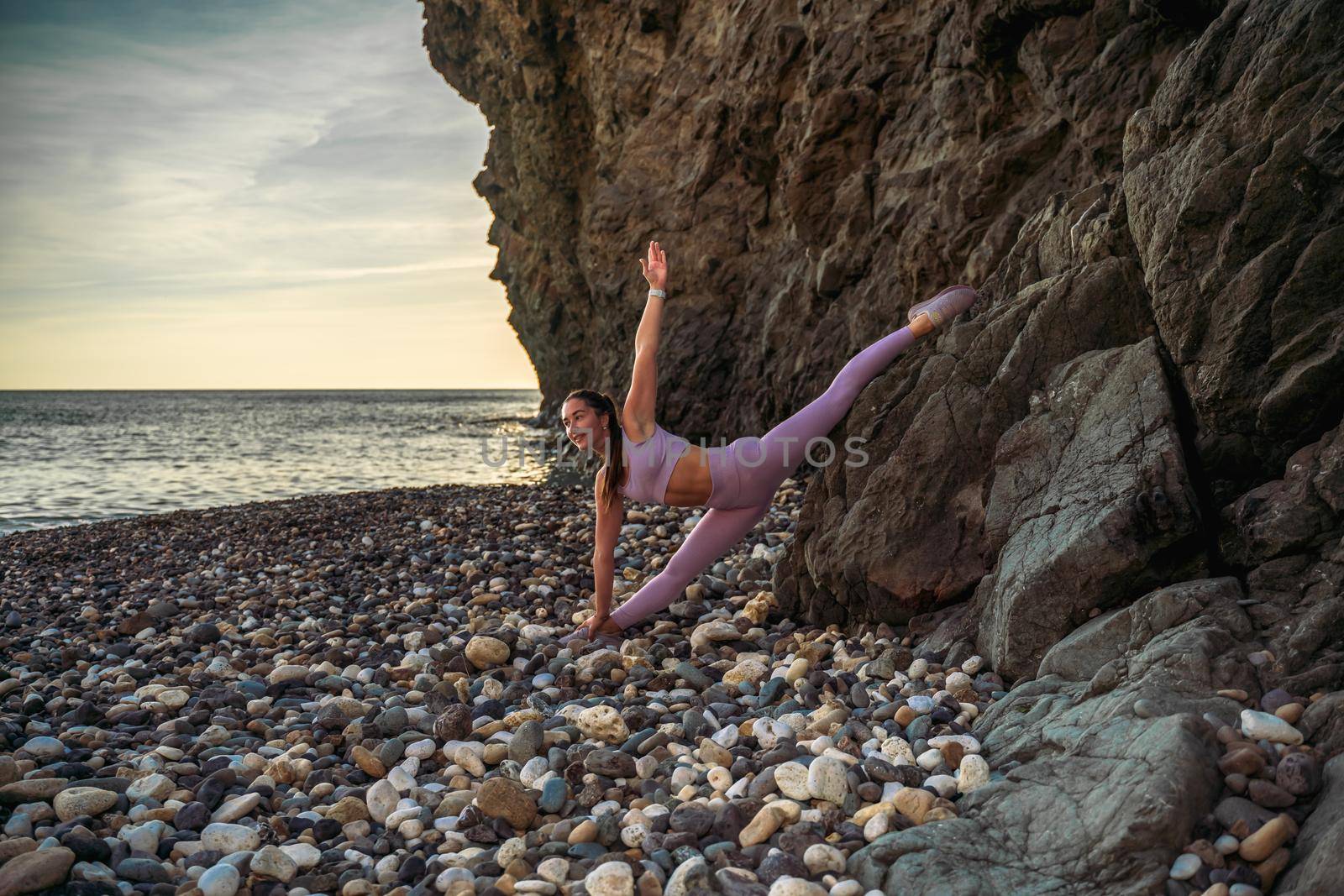 Girl gymnast is training on the beach by the sea. Does twine. Photo series.