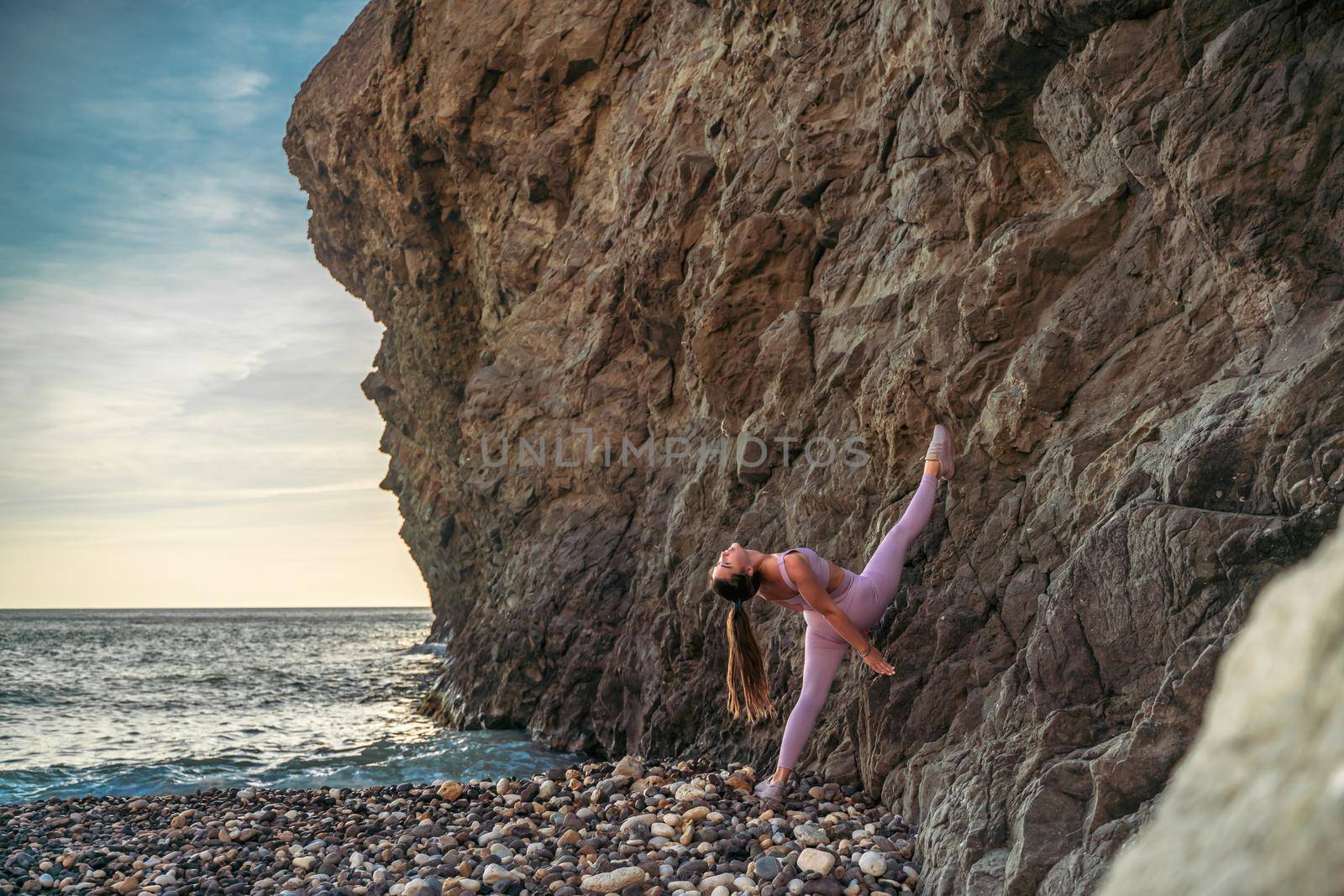 Girl gymnast is training on the beach by the sea. Does twine. Photo series.
