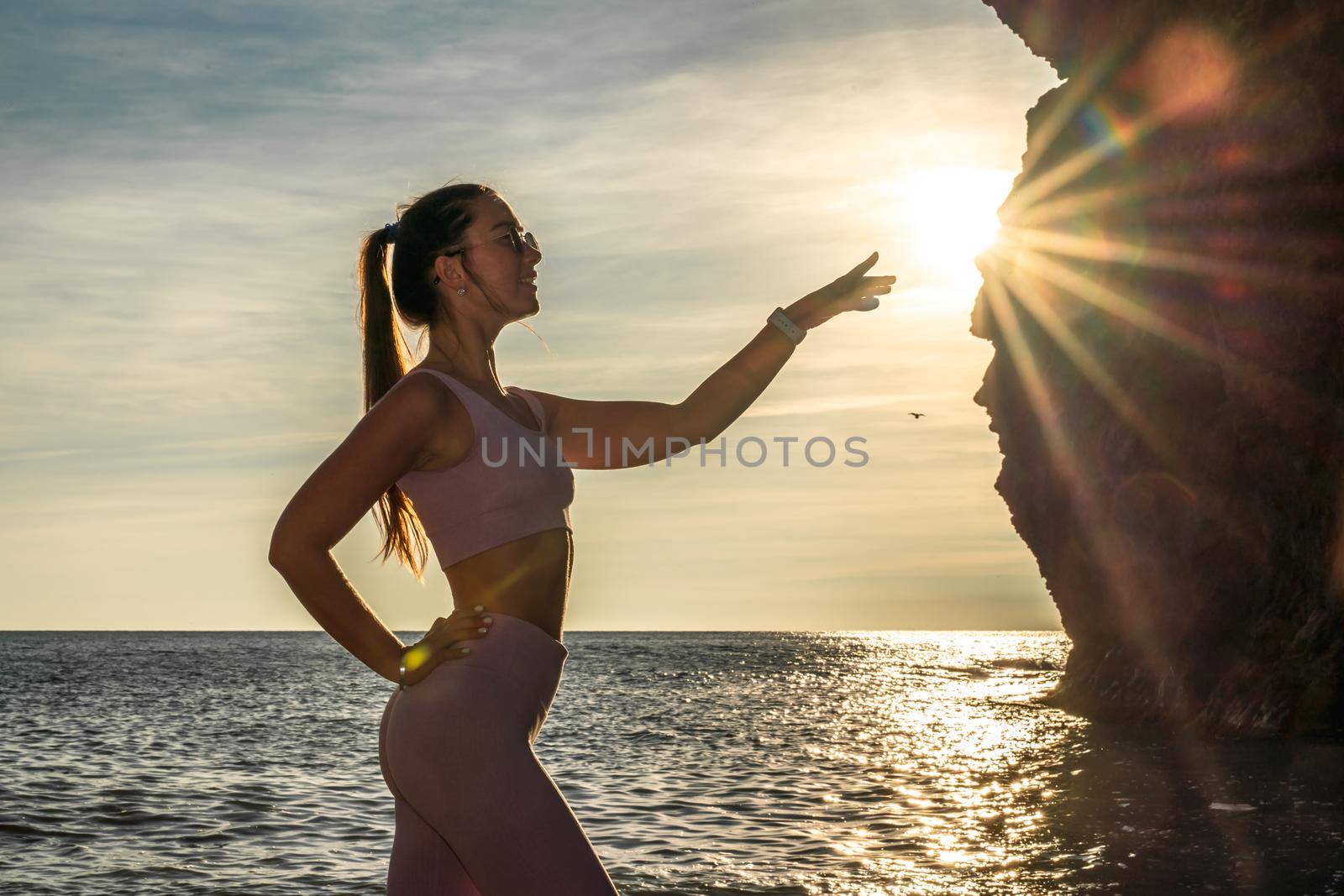 Girl gymnast is training on the beach by the sea sunset. Does twine. Photo series