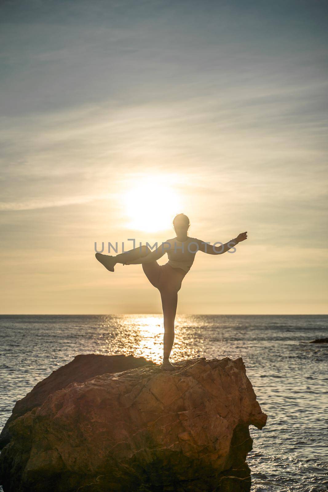 Girl gymnast is training on the beach by the sea sunset. Does twine. Photo series