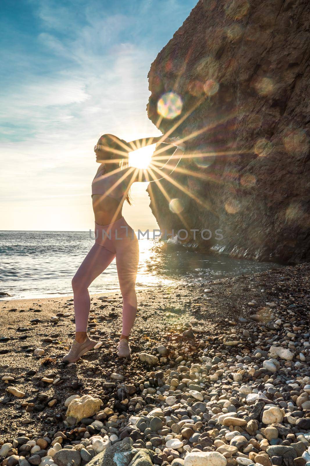 Girl gymnast is training on the beach by the sea sunset. Does twine. Photo series