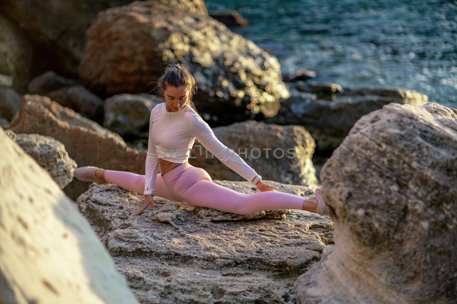 Girl gymnast is training on the beach by the sea. Does twine. Photo series.