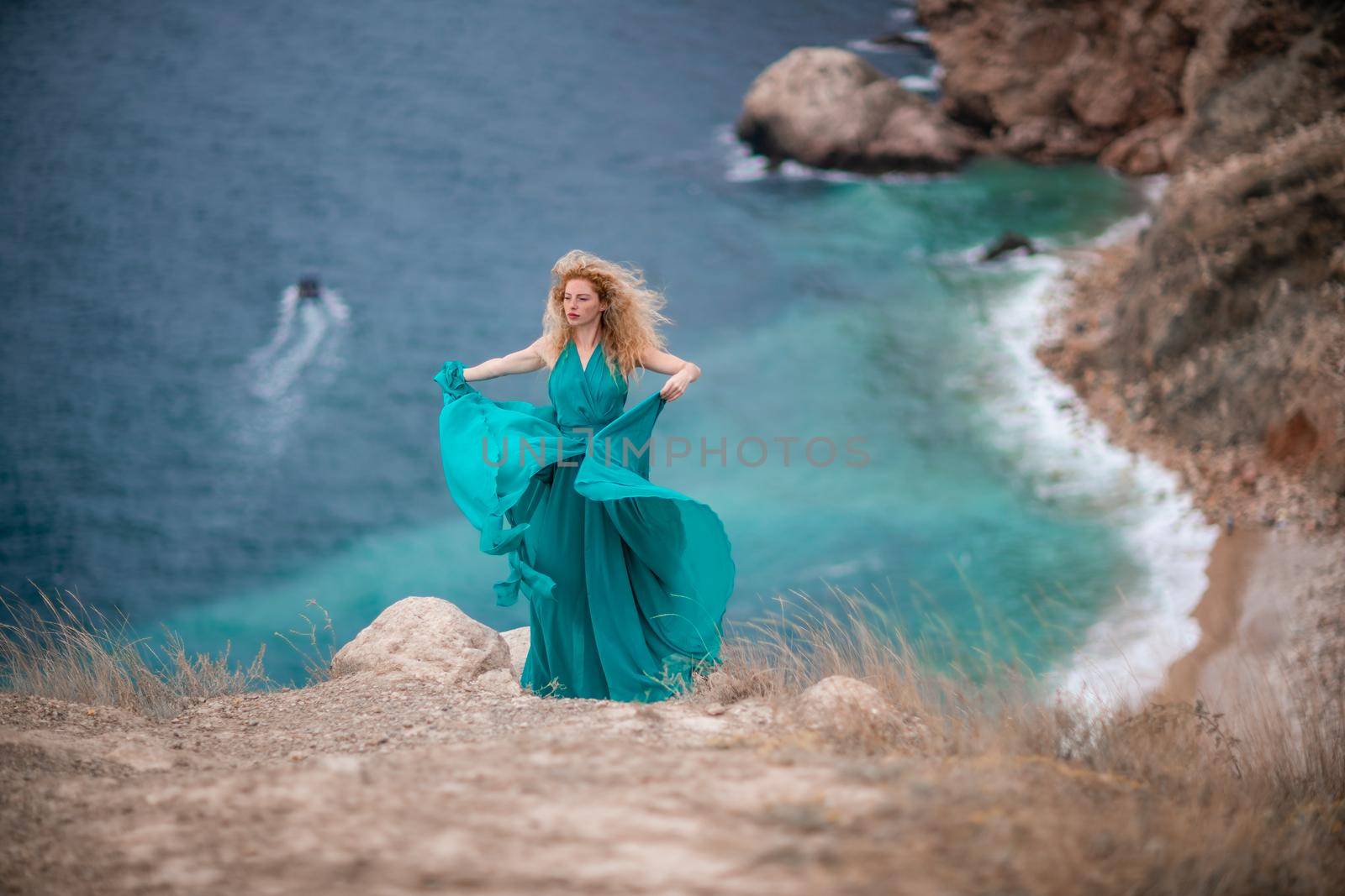 A woman in an emerald dress, a fashion model with long silk wings in a flowing dress, flying fabric on the embankment. by Matiunina