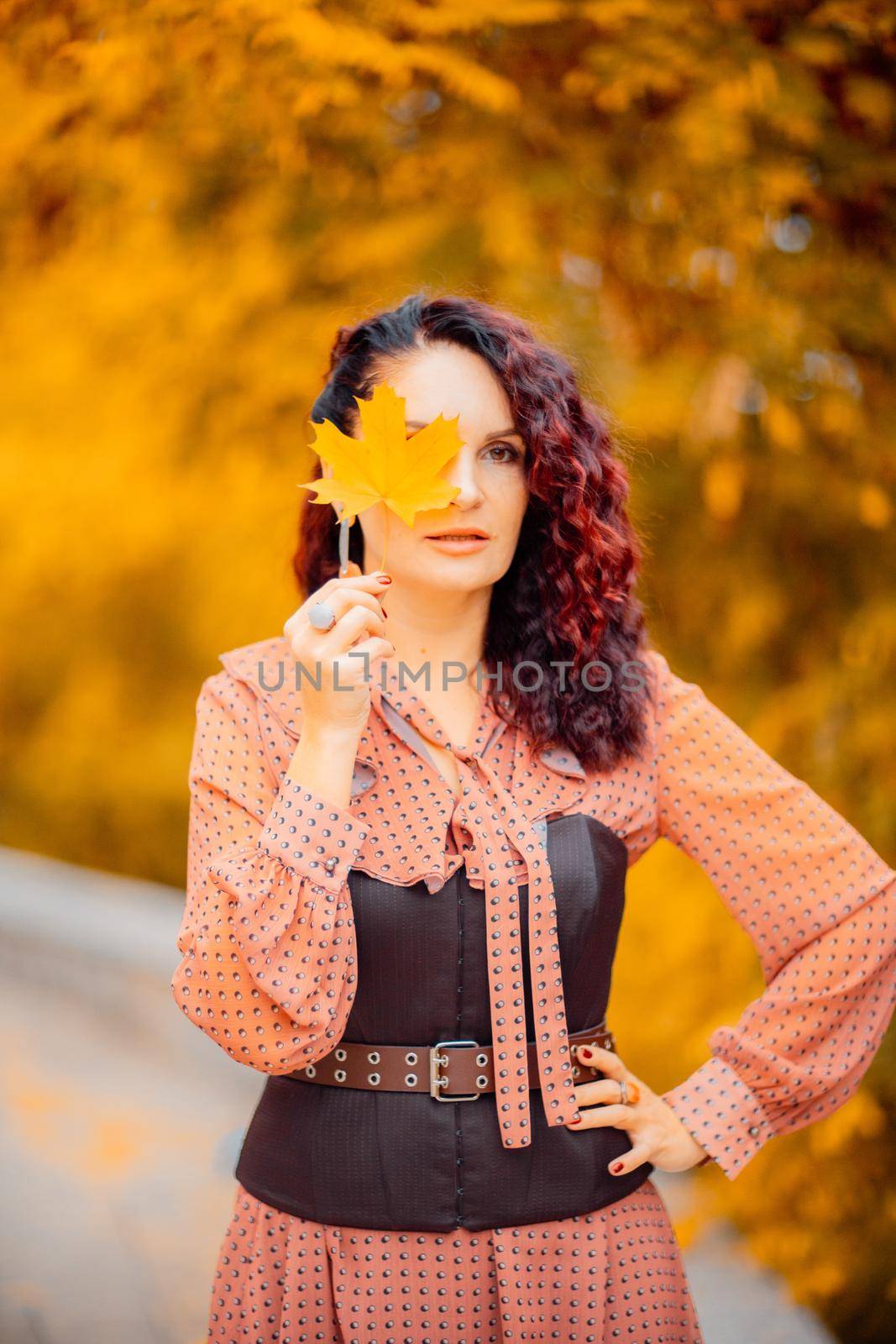 Beautiful girl walking outdoors in autumn. Smiling girl collects yellow leaves in autumn. Young woman enjoying autumn weather