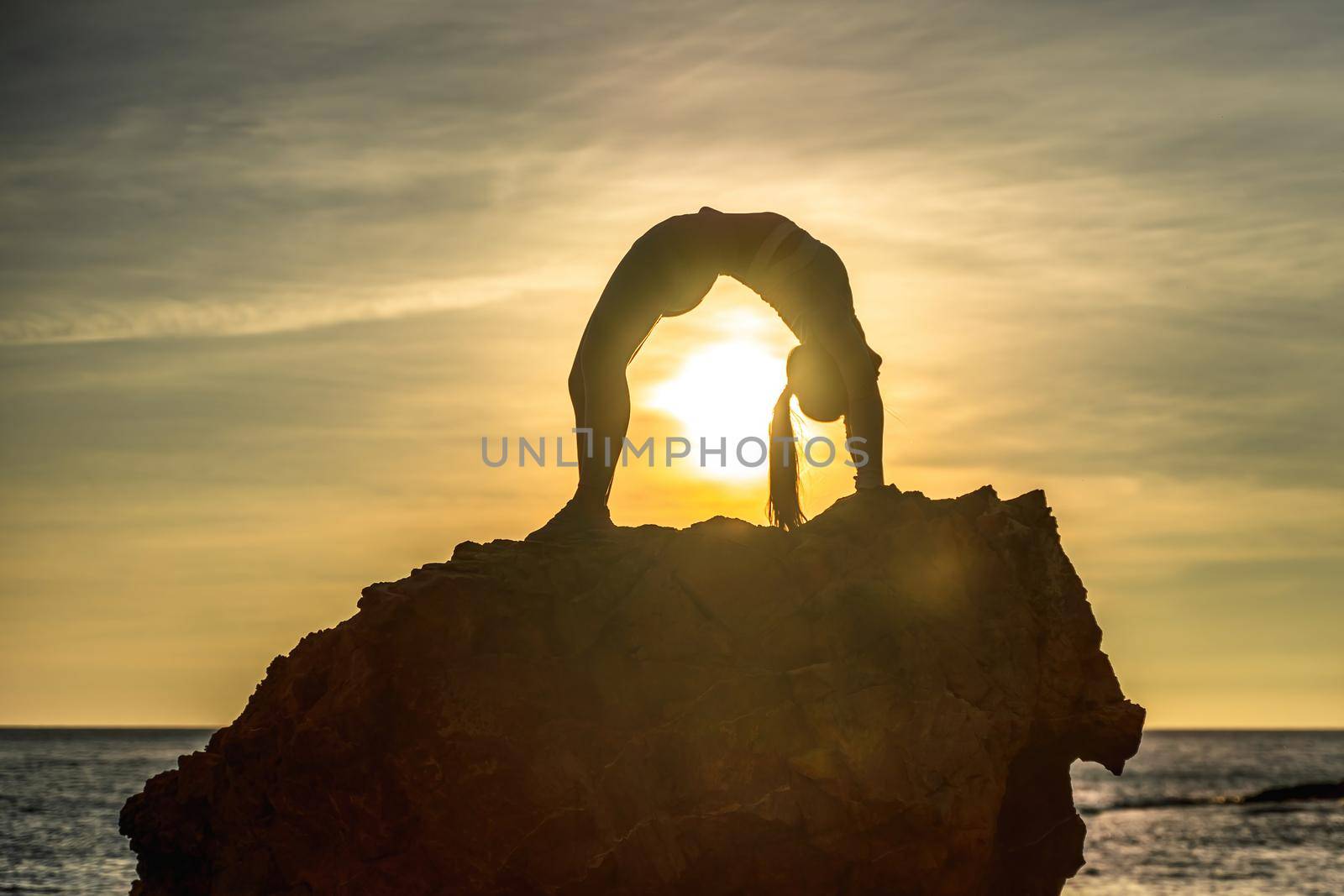 Girl gymnast is training on the beach by the sea sunset. Does twine. Photo series. by Matiunina