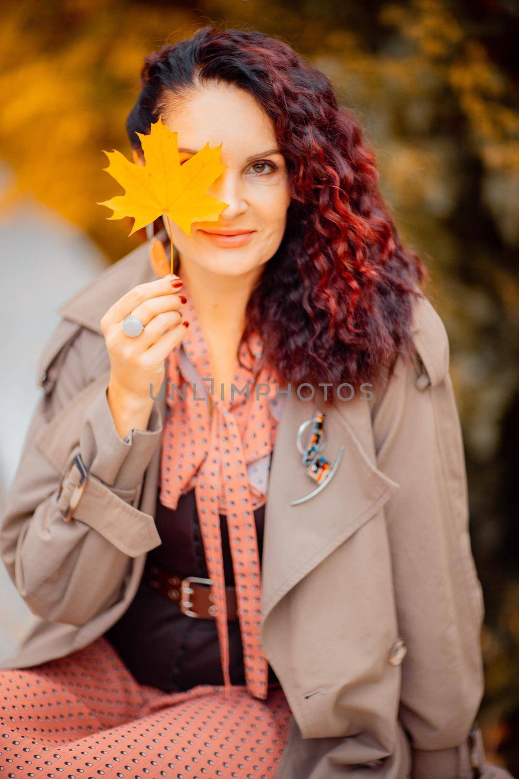 Beautiful girl walking outdoors in autumn. Smiling girl collects yellow leaves in autumn. Young woman enjoying autumn weather. by Matiunina