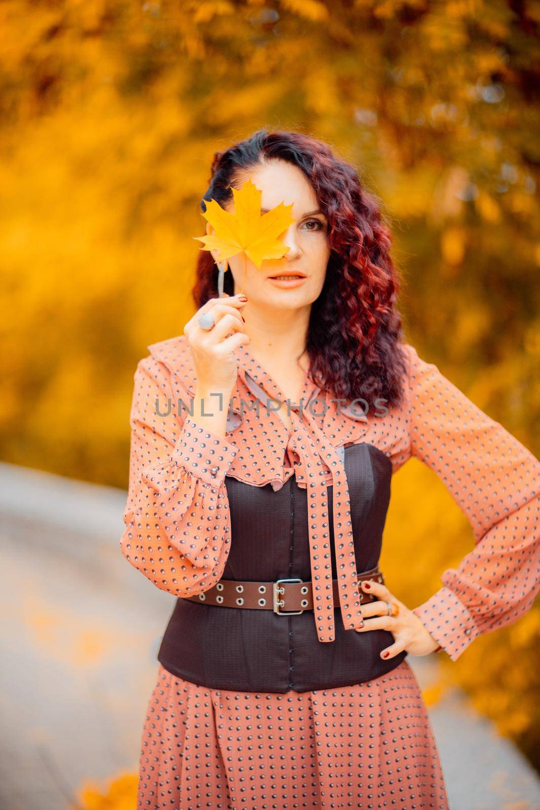 Beautiful girl walking outdoors in autumn. Smiling girl collects yellow leaves in autumn. Young woman enjoying autumn weather