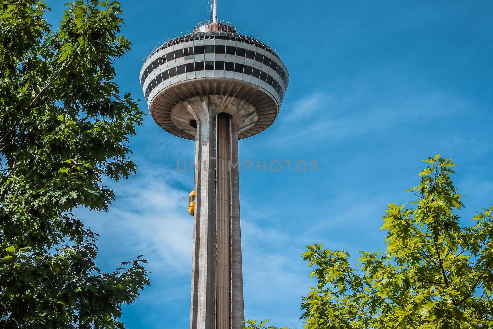 Niagara Falls, Ontario Canada - August 29, 2019: Beautiful view of skylon tower at Niagara falls with blue sky and green trees. by JuliaDorian