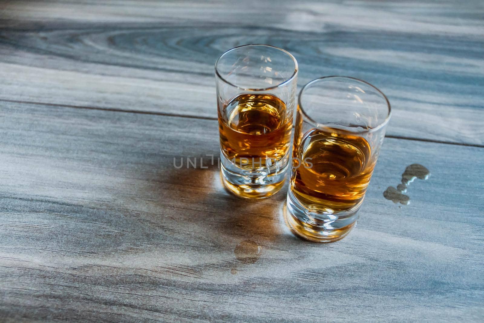 Two shot glasses with whiskey on a wood by JuliaDorian