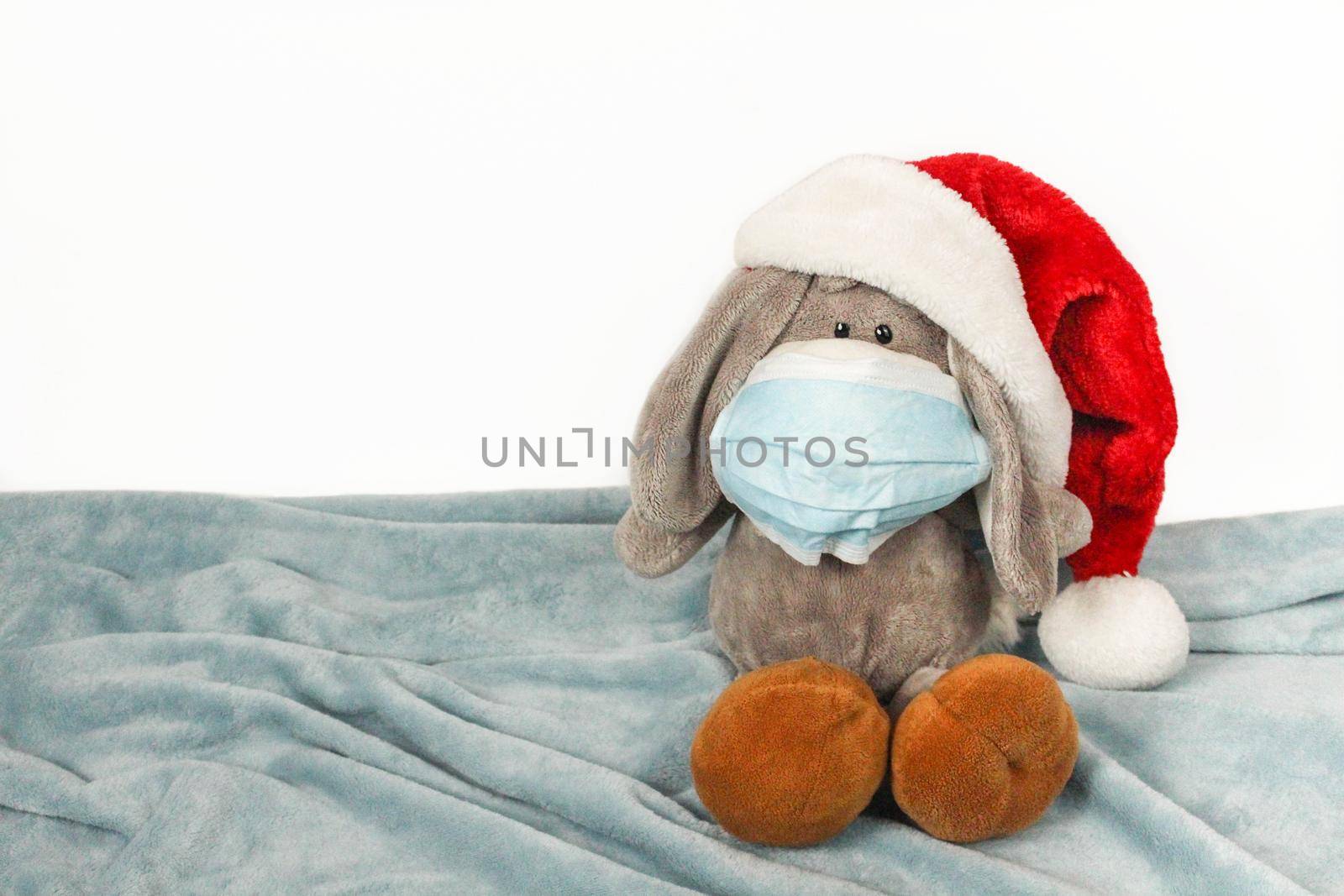 Plush toy in a mask and Christmas hat. Flu colds disease virus bacterium. Plush donkey toy wear protection mask and Santa hat, Protect Against Coronavirus concept